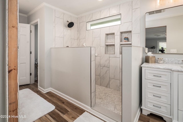 bathroom with vanity, hardwood / wood-style floors, crown molding, and tiled shower