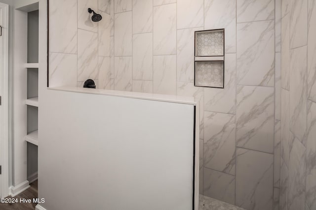 bathroom with a tile shower, hardwood / wood-style floors, and built in features