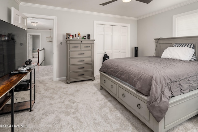 carpeted bedroom featuring ornamental molding, a closet, and ceiling fan