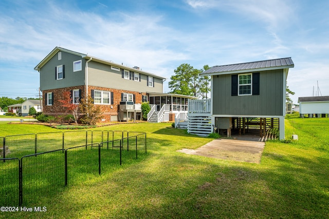 rear view of house featuring a yard and a sunroom