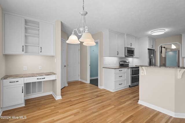 kitchen with white cabinets, light hardwood / wood-style flooring, stainless steel appliances, and decorative light fixtures