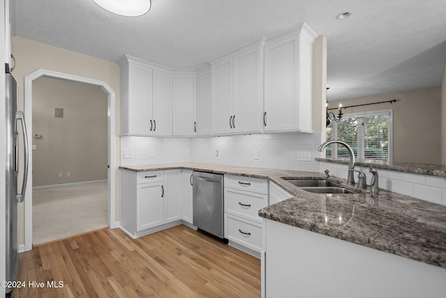 kitchen featuring sink, light hardwood / wood-style floors, stainless steel appliances, dark stone counters, and white cabinets