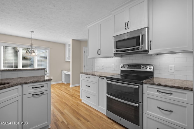 kitchen with light hardwood / wood-style flooring, stainless steel appliances, backsplash, a chandelier, and white cabinets