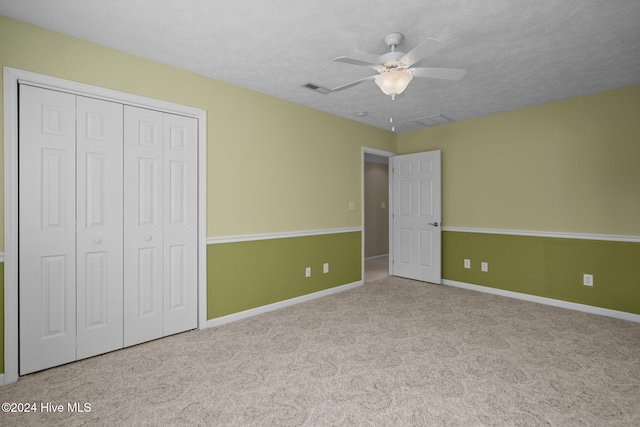 unfurnished bedroom with light carpet, a textured ceiling, a closet, and ceiling fan