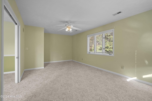 carpeted spare room featuring ceiling fan