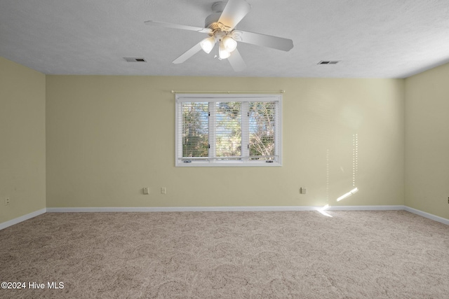 carpeted empty room with ceiling fan and a textured ceiling