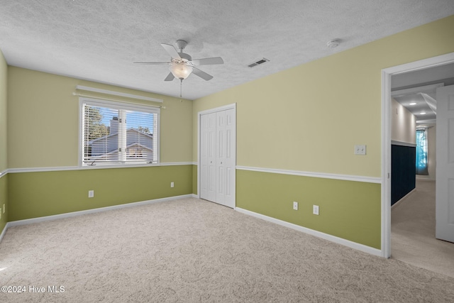 carpeted empty room featuring a textured ceiling and ceiling fan