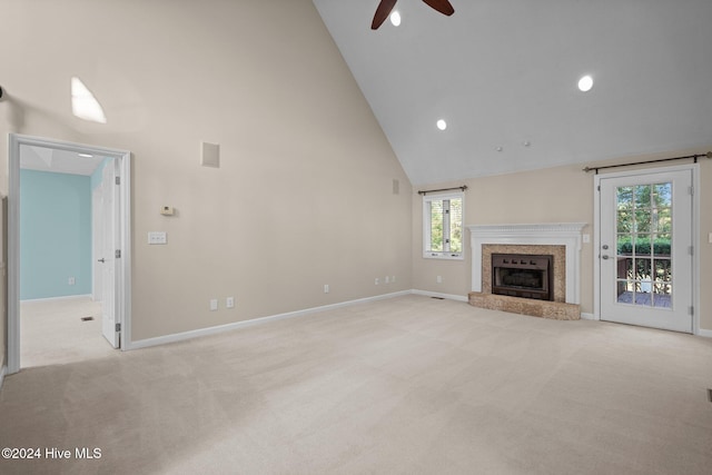 unfurnished living room with a premium fireplace, light carpet, high vaulted ceiling, and plenty of natural light