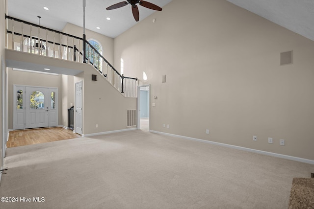 unfurnished living room featuring a healthy amount of sunlight, light wood-type flooring, high vaulted ceiling, and ceiling fan