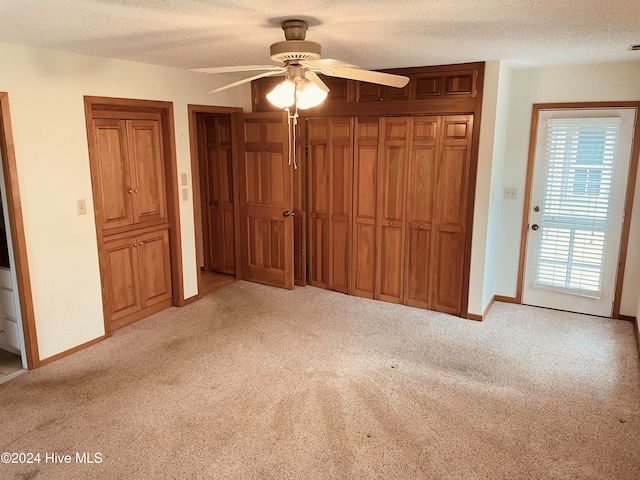 unfurnished bedroom featuring a textured ceiling, light colored carpet, and ceiling fan