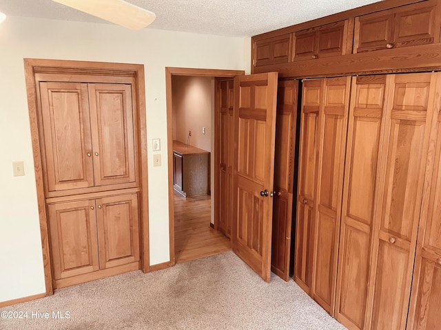 hallway with a textured ceiling and light colored carpet