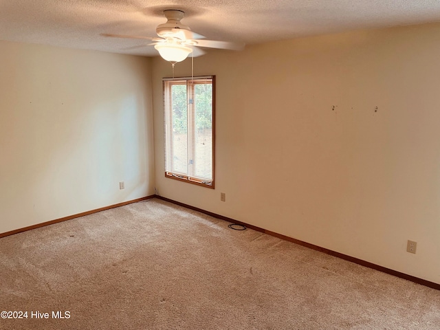 spare room with a textured ceiling, carpet floors, and ceiling fan