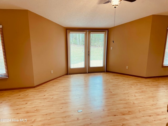 spare room featuring ceiling fan, light wood-type flooring, a textured ceiling, and french doors