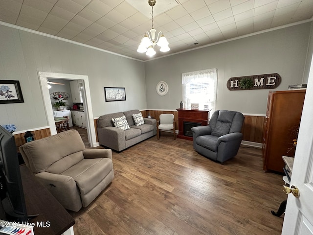 living room with ornamental molding, a chandelier, hardwood / wood-style flooring, and wood walls