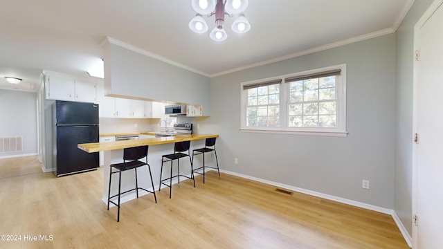 kitchen featuring stainless steel appliances, a kitchen breakfast bar, light hardwood / wood-style flooring, kitchen peninsula, and white cabinets