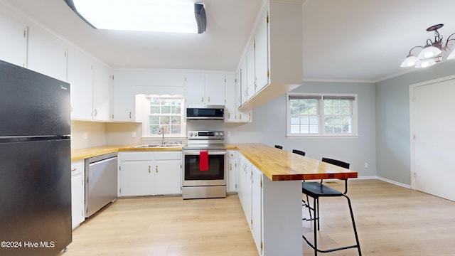 kitchen with stainless steel appliances, white cabinetry, and a wealth of natural light