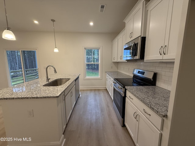 kitchen with stainless steel appliances, backsplash, hanging light fixtures, white cabinets, and sink