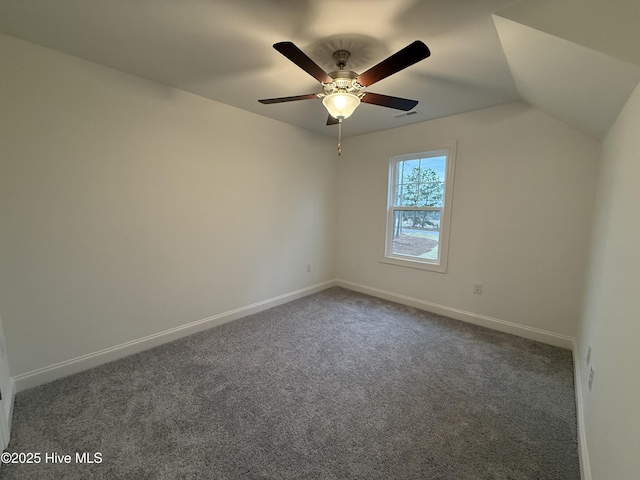 spare room featuring ceiling fan, vaulted ceiling, and dark colored carpet