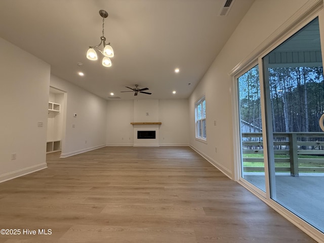 unfurnished living room featuring a fireplace, ceiling fan with notable chandelier, and light hardwood / wood-style flooring