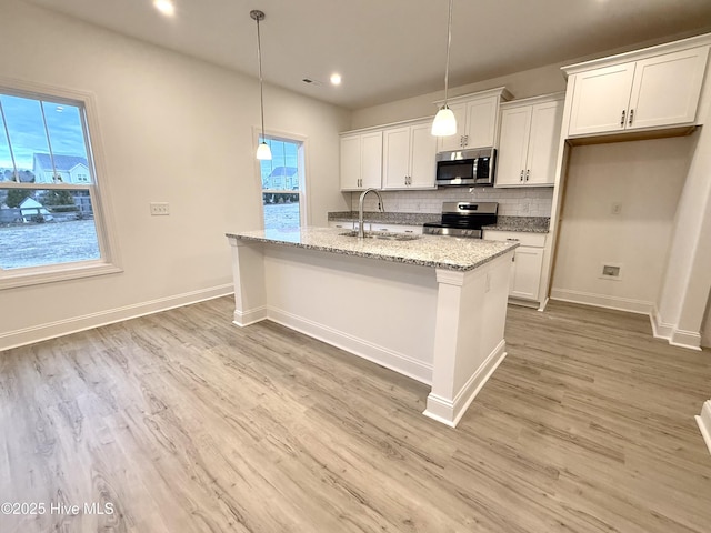 kitchen with light stone countertops, appliances with stainless steel finishes, and white cabinetry