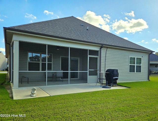 rear view of property featuring a sunroom, a patio area, and a lawn