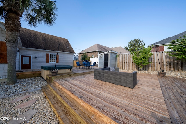 wooden deck featuring outdoor lounge area, a shed, and a hot tub