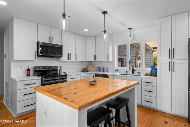 kitchen with black appliances, a kitchen island, white cabinetry, and pendant lighting