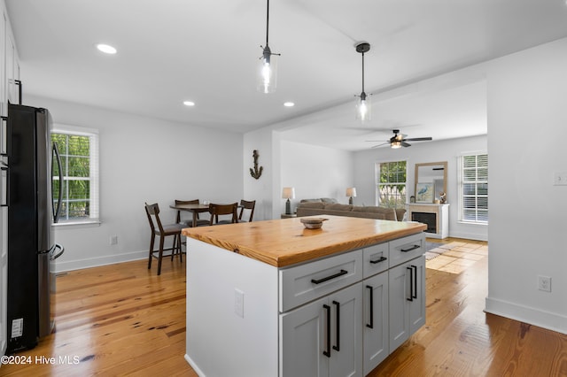 kitchen featuring hanging light fixtures, stainless steel fridge, light hardwood / wood-style floors, and plenty of natural light