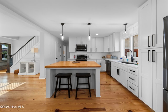 kitchen featuring a kitchen breakfast bar, stainless steel appliances, sink, white cabinets, and a kitchen island