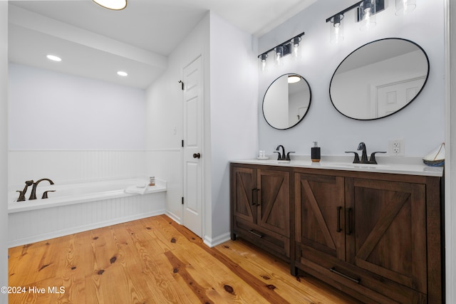 bathroom featuring hardwood / wood-style flooring, vanity, and a tub to relax in