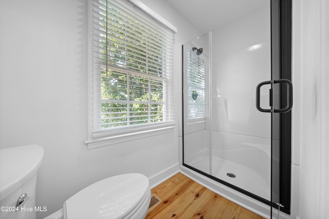 bathroom featuring hardwood / wood-style floors, toilet, and a shower with shower door