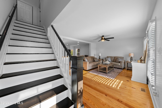 staircase featuring ceiling fan and wood-type flooring