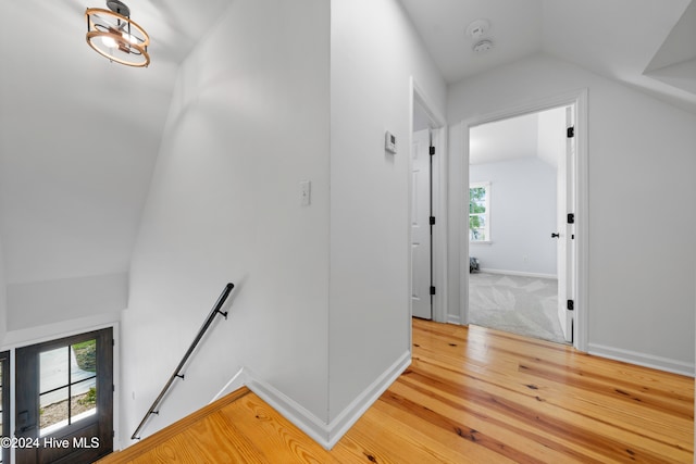 corridor with hardwood / wood-style floors and lofted ceiling