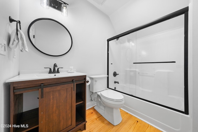 full bathroom with bath / shower combo with glass door, vaulted ceiling, toilet, vanity, and hardwood / wood-style flooring