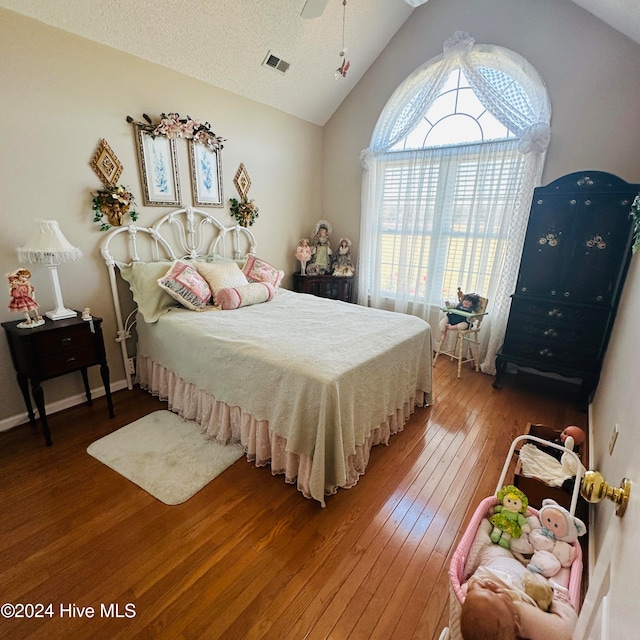 bedroom featuring ceiling fan, hardwood / wood-style flooring, a textured ceiling, and vaulted ceiling