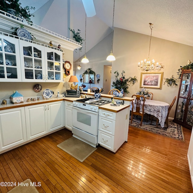 kitchen with light hardwood / wood-style flooring, white gas range oven, kitchen peninsula, pendant lighting, and white cabinets