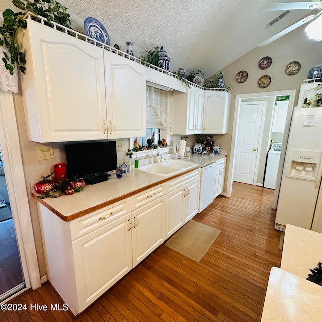 kitchen featuring white cabinetry, a textured ceiling, wood-type flooring, vaulted ceiling, and sink