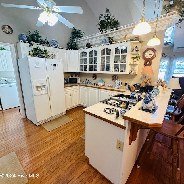 kitchen featuring washer / dryer, pendant lighting, high vaulted ceiling, and white fridge with ice dispenser