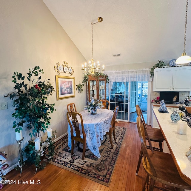 dining space with a notable chandelier, lofted ceiling, and hardwood / wood-style floors