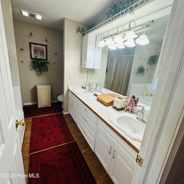 bathroom featuring vanity, toilet, a textured ceiling, and hardwood / wood-style floors