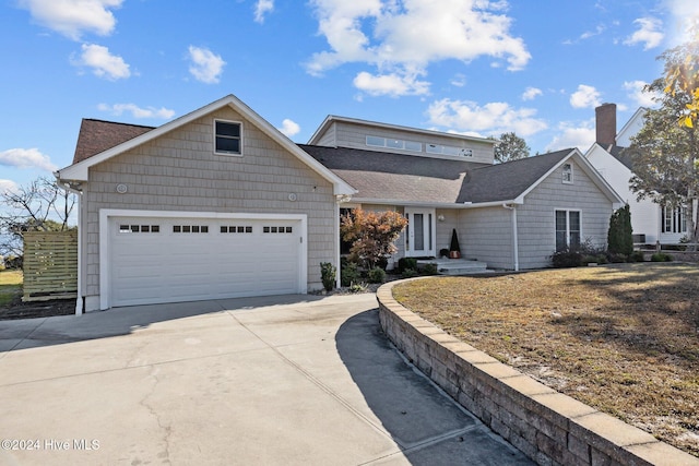 view of front of property featuring concrete driveway, a shingled roof, and an attached garage