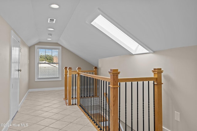 interior space with lofted ceiling with skylight and light tile patterned floors