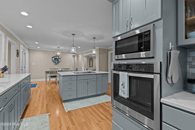 kitchen with stainless steel appliances, light wood finished floors, gray cabinets, and crown molding