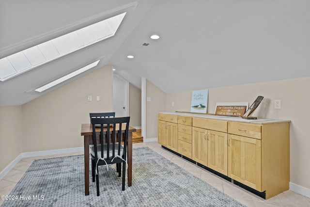 dining space with lofted ceiling with skylight and light tile patterned flooring