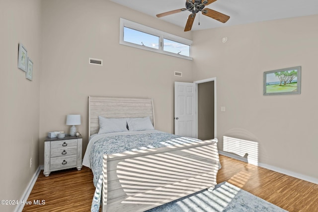 bedroom featuring hardwood / wood-style floors, a high ceiling, and ceiling fan