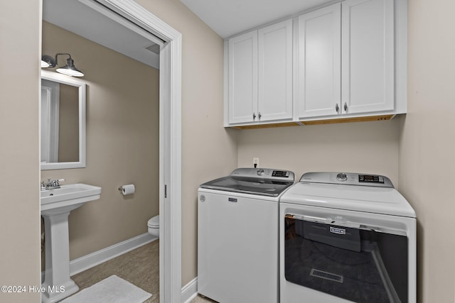 clothes washing area with cabinets and washing machine and dryer