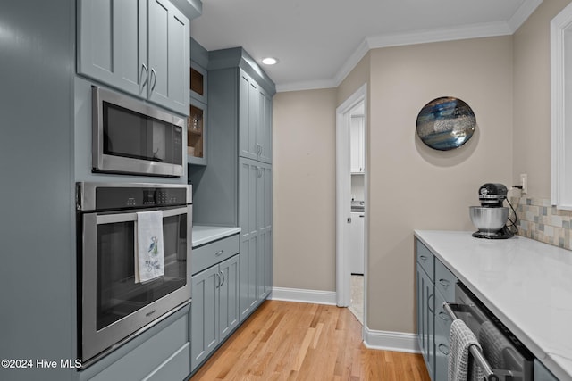 kitchen with crown molding, appliances with stainless steel finishes, light wood-type flooring, and decorative backsplash