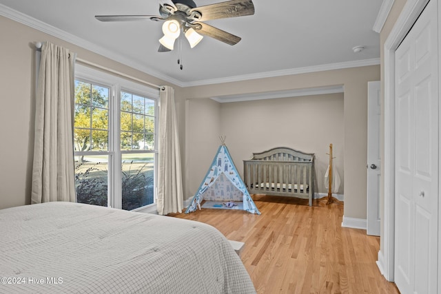 bedroom with a closet, hardwood / wood-style flooring, crown molding, and ceiling fan