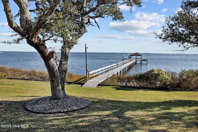 view of dock with a yard and a water view