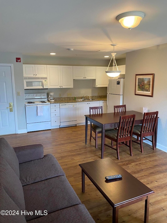 kitchen featuring white appliances, white cabinetry, light hardwood / wood-style flooring, and hanging light fixtures